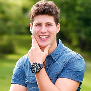 a smiling man wearing a blue shirt and a black watch